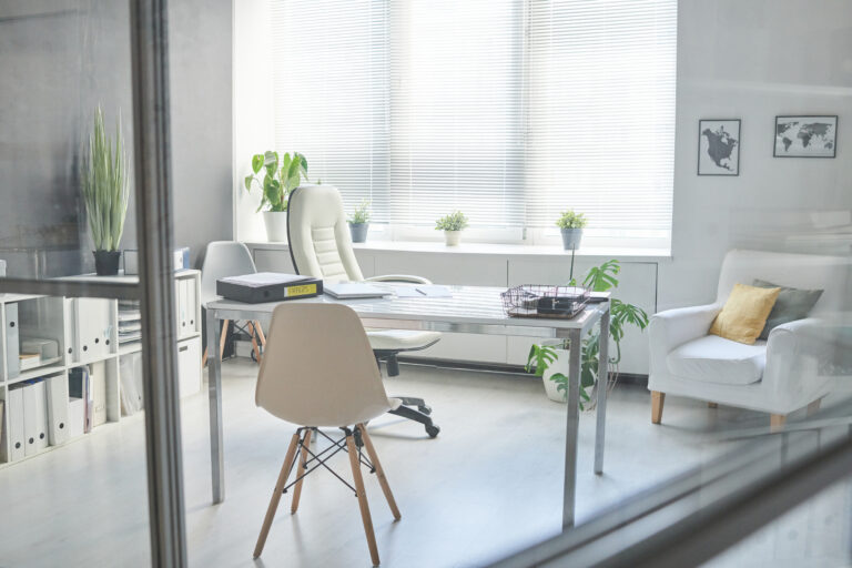 No people through glass shot of minimalistic workplace interior in modern office room in white colour
